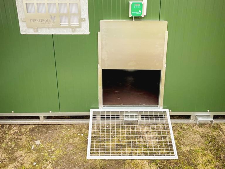 Eine Metall-Luke mit Gittern ist an der unteren Seite einer grünen Wand montiert.