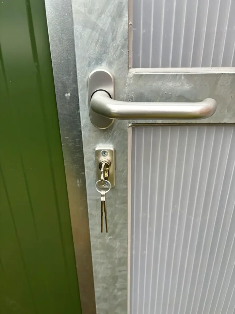 Schloss und Türgriff an einer abschließbaren metallenen Tür.