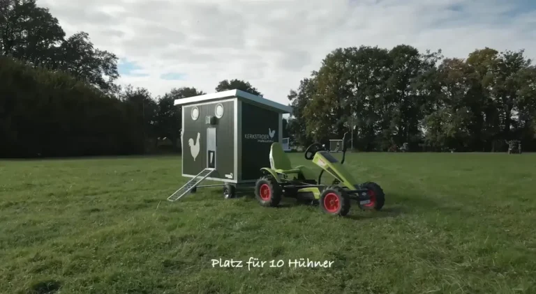 Ein Hühnerhaus mit Platz für zehn Hühner steht auf einer Wiese, daneben befindet sich ein kleiner grüner Traktor.
