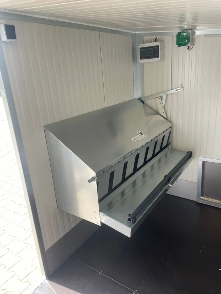 Das Bild zeigt das Innere eines 40er-Familiennests mit einem grauen, metallischen Futtersilo an der Wand.