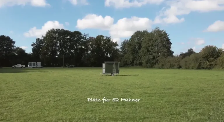 Ein Hühnerstall auf einer grünen Wiese mit einem Schriftzug, der Platz für 52 Hühner anzeigt.